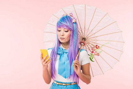 亚裔女孩持有纸伞使用在粉红色上隔图片