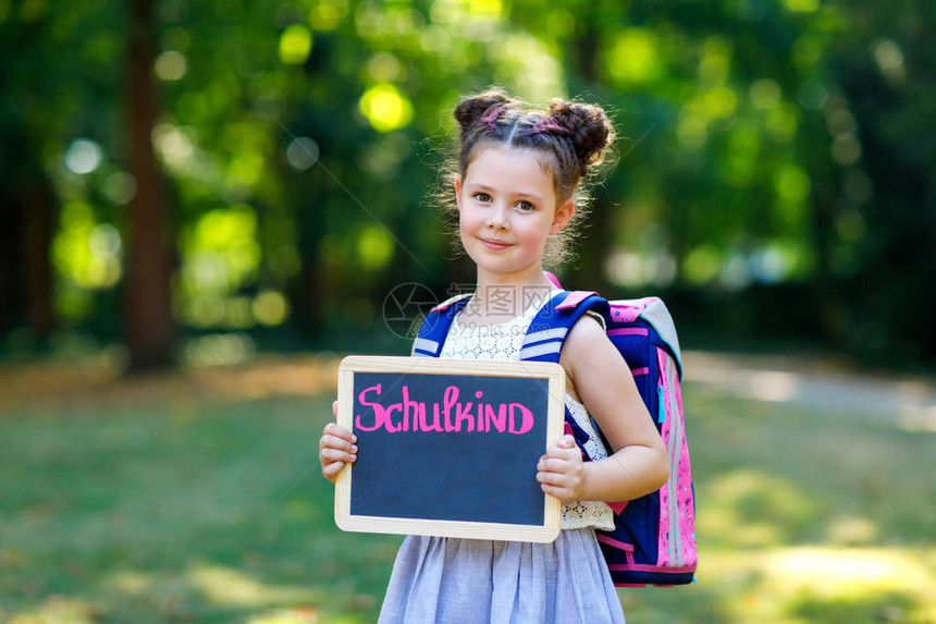 快乐的小女孩站在桌子和背包或书包旁小学第一天的小学生户外健康可爱的孩子图片