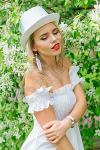 穿着白色圆帽的感现代新娘在春日将鲜花图片
