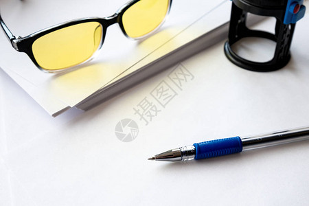 白色背景眼镜和白纸旁边印的钢笔上的钢笔图片