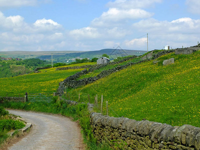 乡下道路的角落向下山坡走去周围环绕着石墙和春草地在日方荒村图片