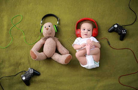 可爱的婴儿男孩与泰迪熊耳机和喜乐板图片