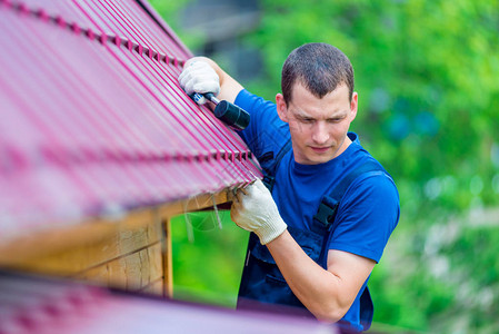 一名男子用锤子修理房屋顶图片
