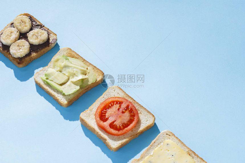 蓝色背景上的奶酪番茄香蕉和鳄梨三明治健康饮食酒店早餐饮食的概念自然采光图片