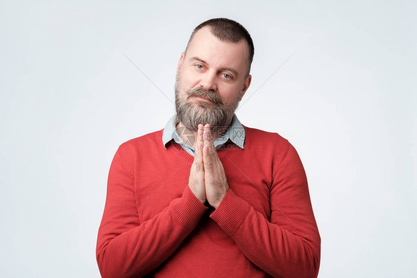 身穿红色毛衣满怀希望的成熟白人男子携手祈祷图片