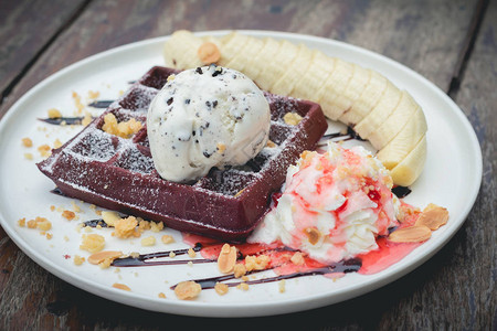 巧克力华夫饼配香草冰淇淋香蕉生奶油和草莓糖浆舒适的户外咖啡馆里的图片