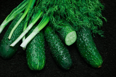 黑色背景的绿色黄瓜洋葱和鹦鹉一些有机熟食蔬菜在图片