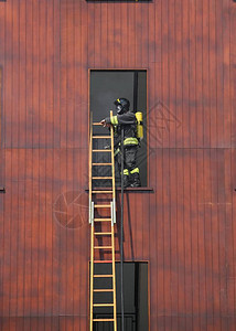 带梯子和氧气瓶的消防员进入大楼背景图片