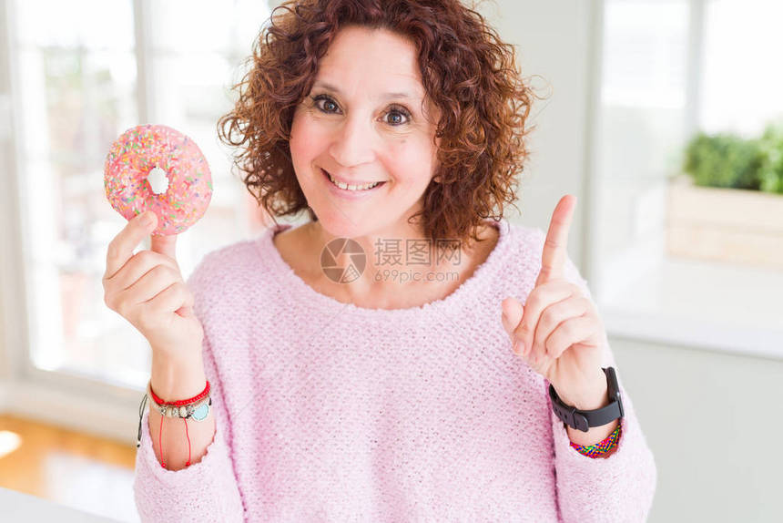 吃粉红糖甜圈的老妇人惊讶于一个想法或问题用快乐的脸对图片