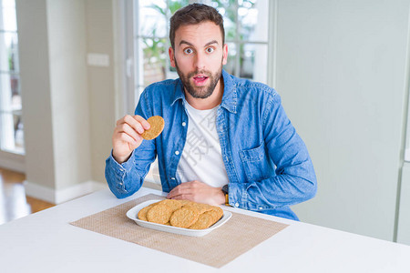 英俊的男人吃着健康的全麦饼干图片