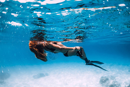 带鳍的女子自由潜水员在海中放松蓝色海洋中的水下图片