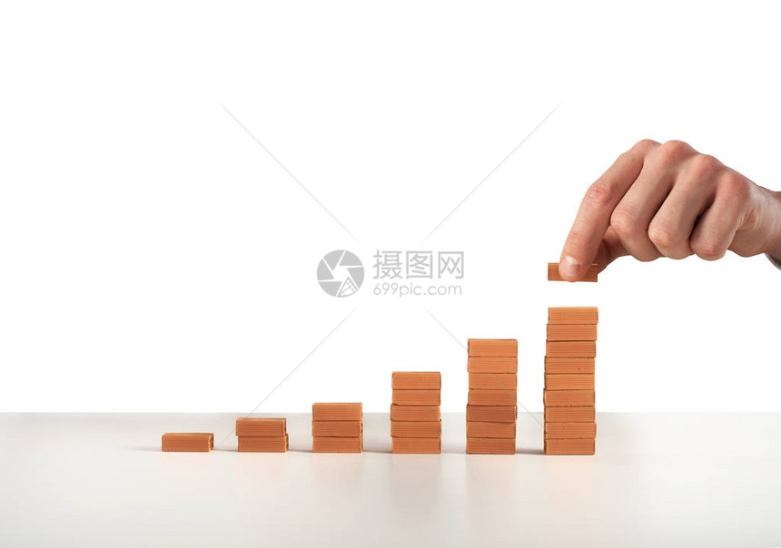 商人把一块砖放在一块静态砖上增长统计和成功的概念图片