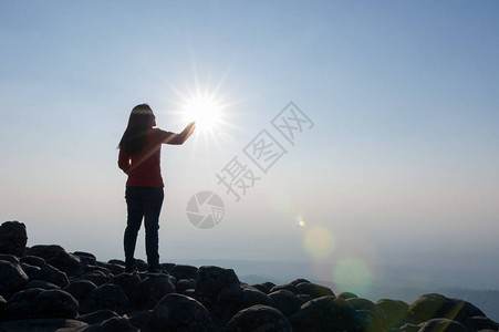 站在悬崖山顶上的年轻女子的剪影图片