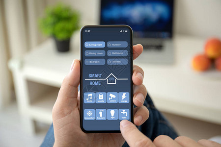 男用手握着手机与应用程序智能家在房间里图片