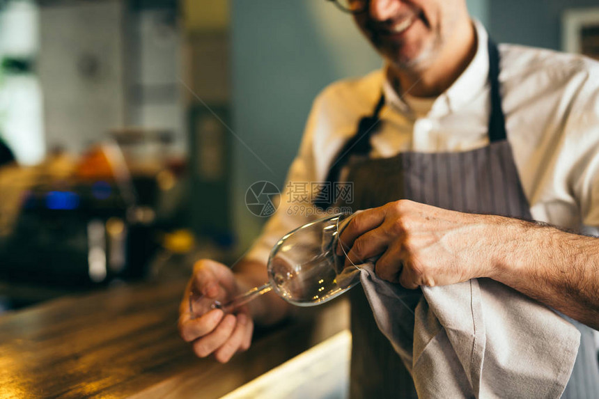 成熟的酒保在咖啡厅擦酒杯图片