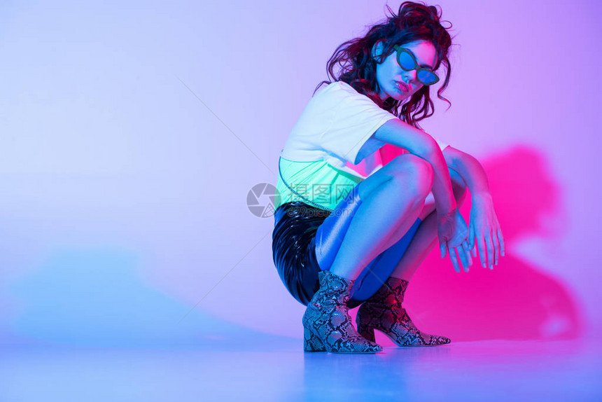 戴太阳镜的时髦女人坐在紫色和图片