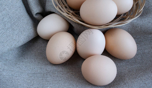 篮子里的鸡蛋亚麻灰色织物上的柳条篮里的鸡蛋特写图片