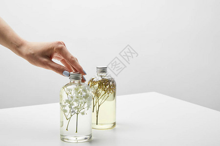白色桌上用有机洗发水触摸瓶子的妇图片