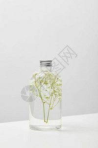 以透明瓶装的有机化妆品产白桌上有草背景图片
