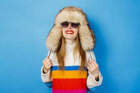 寒假招生广告一个戴着毛皮帽眼镜和蓝色背景毛衣的快乐脸的女孩冬季寒假背景
