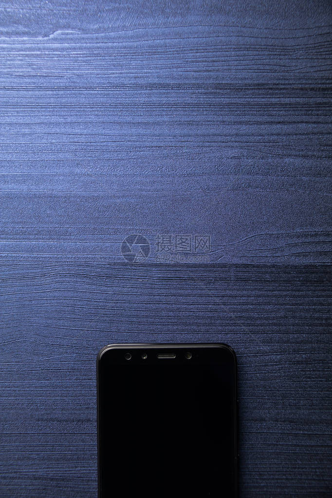 一个带相机的黑色现代智能手机关闭蓝色木图片