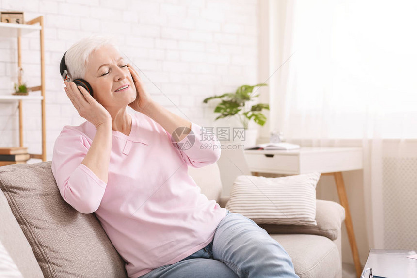 享受耳机空间音频书的年长妇女图片