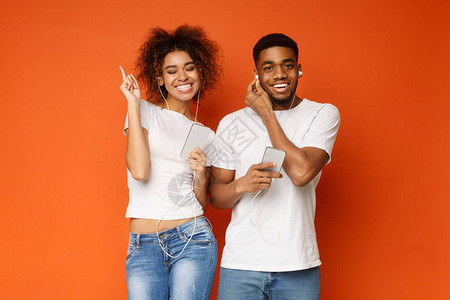 最喜爱的音乐应用积极的非洲美籍夫妇通过手机橙色背景听耳语中的音乐图片