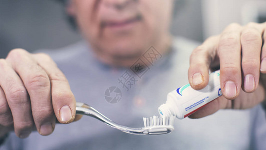 男人从牙刷上的管子里挤出牙膏背景图片