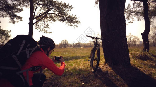 年轻的高加索女运动员旅游自行车手在电话上拍照图片