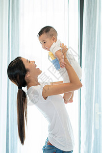 母亲在客厅抱着孩子与婴儿一起玩耍图片
