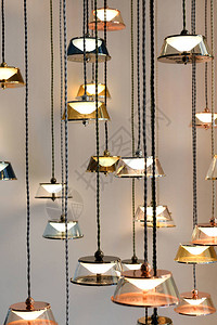 许多现代设计带照明灯挂在长的黑铁丝线上并挂在灰墙图片