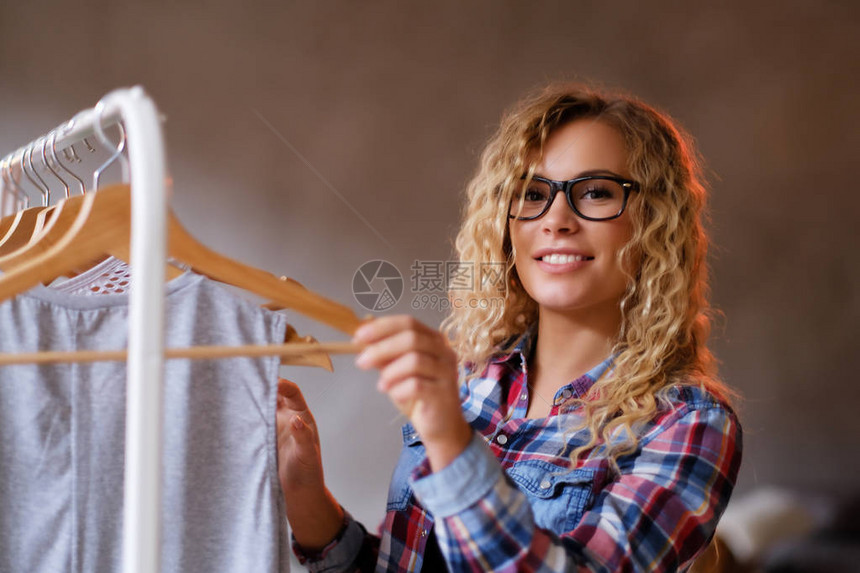 戴着眼镜和格子衬衫的微笑快乐女人为她的假期选择衣服图片