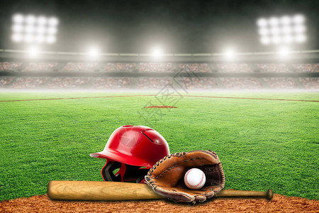 棒球头盔球棒手套和球在灯火通明的户外体育场专注于背景和复制空间的图片