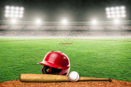 棒球头盔球棒和球在灯火通明的户外体育场专注于背景和复制空间的图片