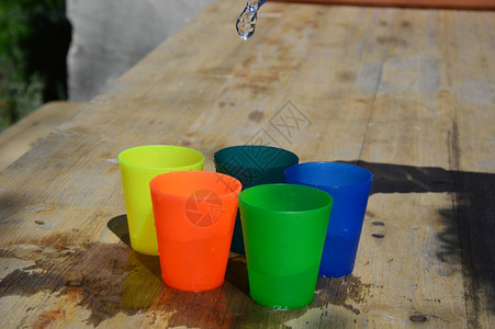 木桌上五颜六色的塑料杯装满水背景图片