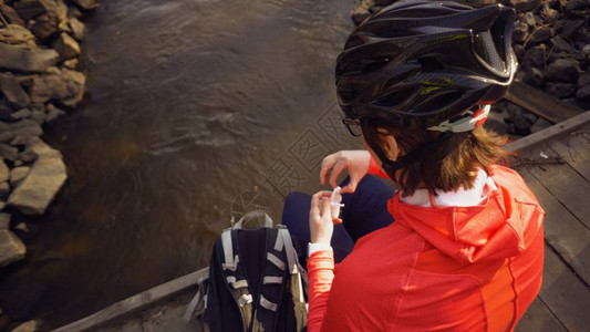 穿戴明亮运动服头盔的高加索女运动员正在河上桥休息图片