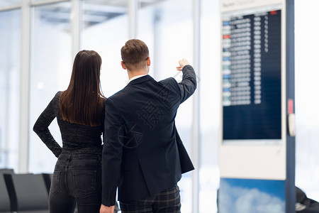 年轻夫妇在国际机场看着航班信息板图片