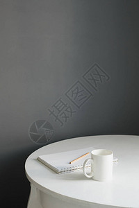 斯堪迪厨房内部的白色木桌上带有素描板和铅笔的咖啡杯图片
