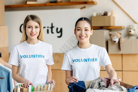 两个漂亮的多元文化志愿者站在纸箱旁边图片