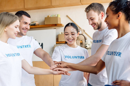 5名多文化青年志愿者在慈善中心微笑和握手背景图片