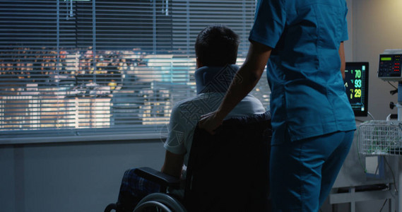 一名护士将十几岁的男病人用轮椅推向窗图片