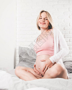 一位快乐的年轻孕妇在早晨躺在床上图片