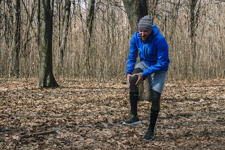 一名穿着训练服的男子在户外锻炼时慢跑时膝盖受伤运动损伤跑步技术错误跑步肌腱炎图片