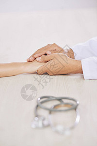 白衣年轻医生的手和他的病人的手背景图片