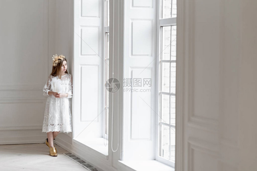 小女孩用金色的发夹做头发和金色的原鞋靠近大窗户的图片