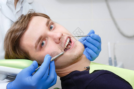 在牙医检查牙齿后坐在顶椅上的年轻图片