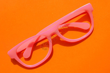 粉红色的塑料眼镜撒谎橙色桌子上戴着眼镜的办公场所带粉色框的眼镜图片