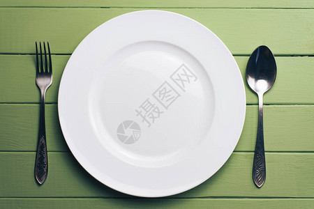 白色板子和一叉子一个勺子在绿图片