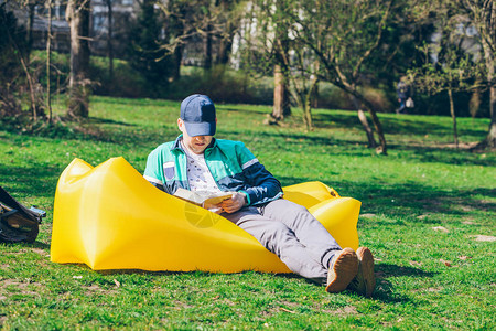 读书概念在城市公园的男人在充气床垫上背景图片