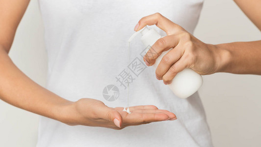 卫生概念女孩从白瓶中抽出乳液图片